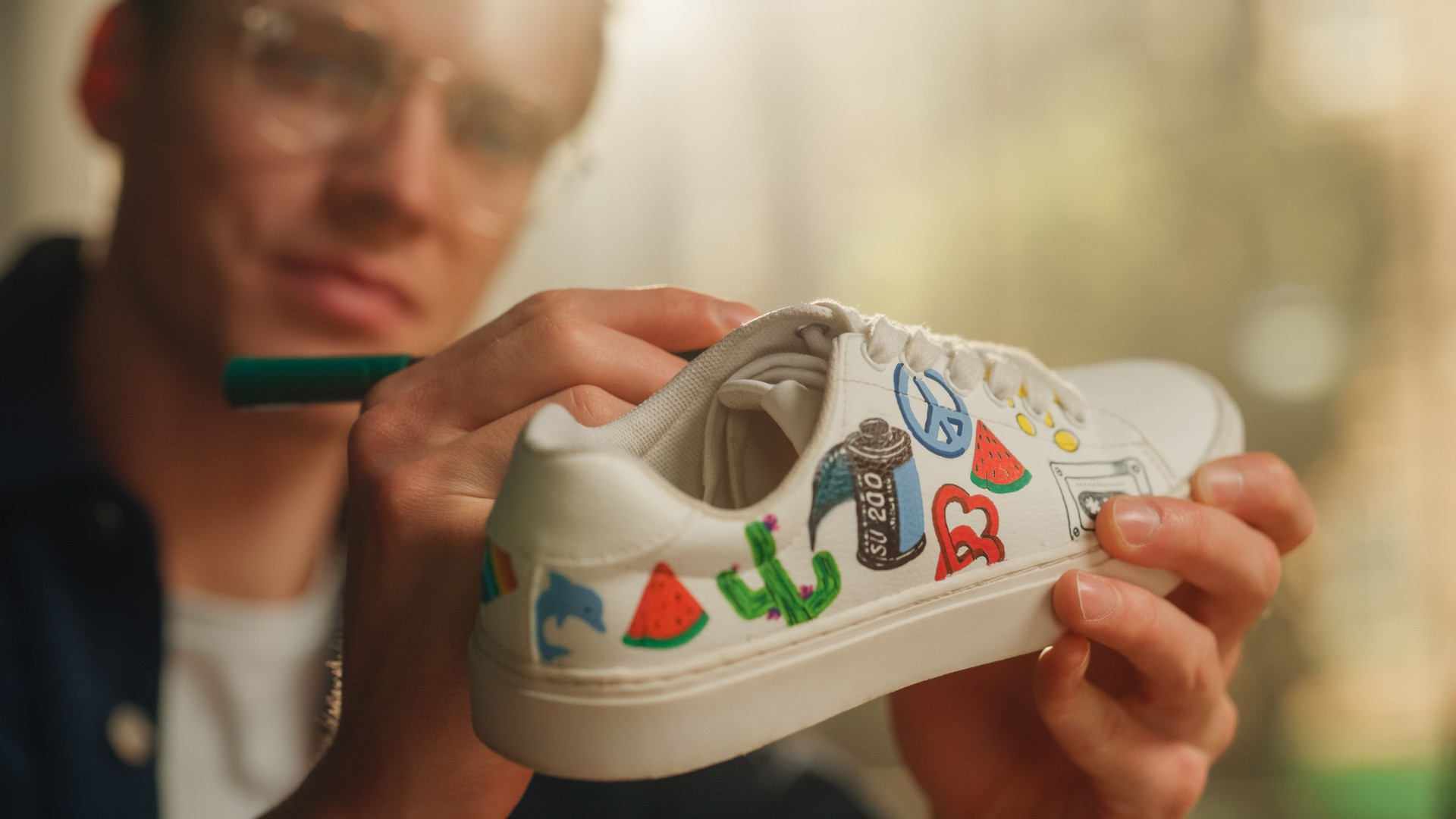 Close Up Portrait of Satisfied Male Artist Refreshing Sneakers by Painting on Them in his Loft Flat. Creative Man Making Custom Made Design for Shoes. Millennial People Concept.